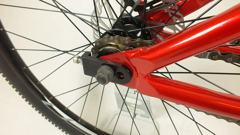 Close-up of rear wheel and chainstay on Salire SJ-50 Dirt Jumper Bike With Disc Brakes And 26 Inch Wheels, red steel frame detail.