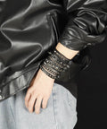 Badass 3 Piece Punk Gothic Leather Bracelet Set With Vintage Steampunk Spikes And Rivets Wide Adjustable Cuff Wristbands For Men And Women Daily Wear Gear worn stacked on wrist with black jacket.