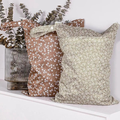 Floral patterned Two Pocket Wet Dry Bag Set With Handle Waterproof Reusable Storage, displayed next to eucalyptus branches.