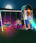 Cedar Wood Swing Set With Nighttime LED Swings And Slide, 2 Person LED Saucer Swing with kids, and play fort under moonlight.