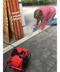 Three Speed Portable Industrial Air Blower With 1200 CFM for fast drying, positioned nearby a worker cutting materials on a job site