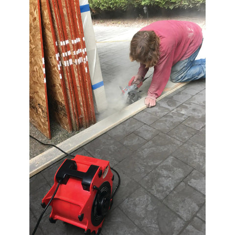 Three Speed Portable Industrial Air Blower With 1200 CFM for fast drying, positioned nearby a worker cutting materials on a job site