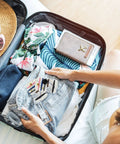 Woman packing a suitcase with On The Go Travel Sewing Kit With Needles, Threads, Buttons And Pins, Six Color Thread Sets, 100 Sets