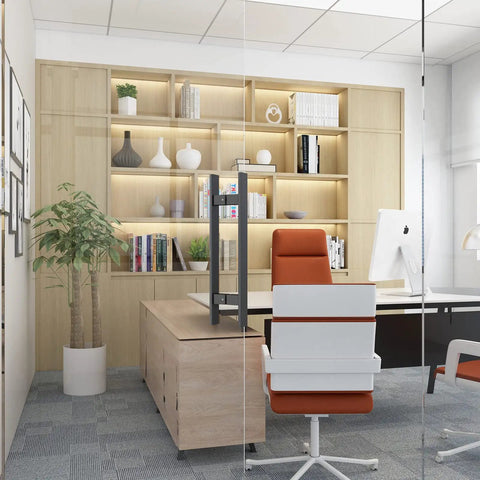 Modern office with glass wall, featuring a red chair, white desk, and wooden shelves with decor and books.