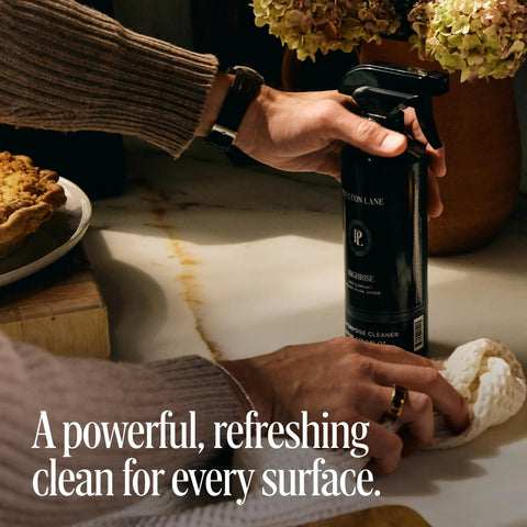 Luxurious All Purpose Cleaner With Doheny Drive Scent, hand using bio-based spray on kitchen counter for streak-free shine
