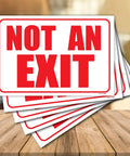 Premium 5 Pack No Exit Sign Decals Featuring Strong Self Adhesive Backing Ideal For Office Doors And Business Spaces Clear Warning Stickers 10 By 7 Inches visible in stack on wooden surface.