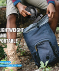 Person placing Must Have All In One Camping Fan With LED Lantern And Aroma Diffuser into a blue backpack outdoors.