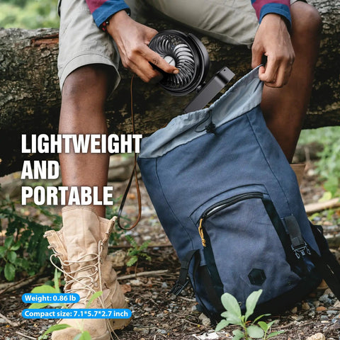 Person placing Must Have All In One Camping Fan With LED Lantern And Aroma Diffuser into a blue backpack outdoors.