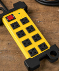 Heavy Duty Shop Workhorse Power Strip With Eight Widely Spaced Outlets And 2700J Surge Protection Six Foot Extension Cord mounted on a wooden surface.