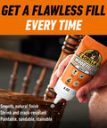 Pro Grade White Wood Filler That Kicks Out Nasty Cracks Holes And Gouges Water Resistant Paint Ready Acrylic Formula Hella Durable Shrink Proof Fast Drying Solid Choice For Home Fixes 6 Oz Tube in hand applying to wood chair.