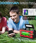 Teens using Emergency Radio With NOAA Weather Radio And AM FM Bands 10000mAh Power Bank USB Solar And Hand Crank Charging in park.