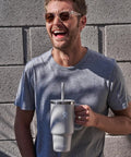 Man smiling while holding On The Fly 40 Oz Stainless Steel Travel Tumbler With Comfort Grip Handle And Leak Proof Straw Lid.