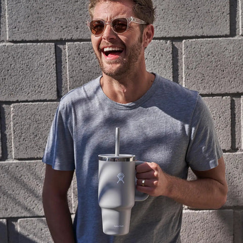 Man smiling while holding On The Fly 40 Oz Stainless Steel Travel Tumbler With Comfort Grip Handle And Leak Proof Straw Lid.