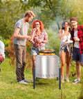 Sturdy Stainless Fire Pit Stand 15 To 27 Inches For Most Outdoor Fire Pits And Camping Stoves Heavy Duty Fire Pit Accessory Elevates Fire Pit Safely Off Ground Silver with group of friends enjoying BBQ.