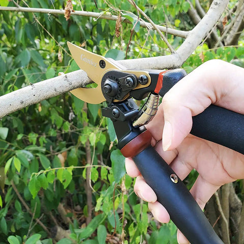 Hand holding 8.5 Inch Rotating Bypass Pruning Shears With Titanium Coated SK5 Blade cutting a thick branch.