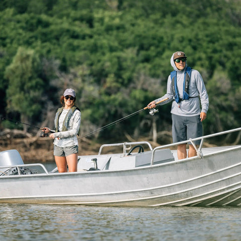 Two people fishing on a boat, wearing USCG Approved Inflatable Life Jacket for Adults Go To Auto Or Manual Inflation Green.