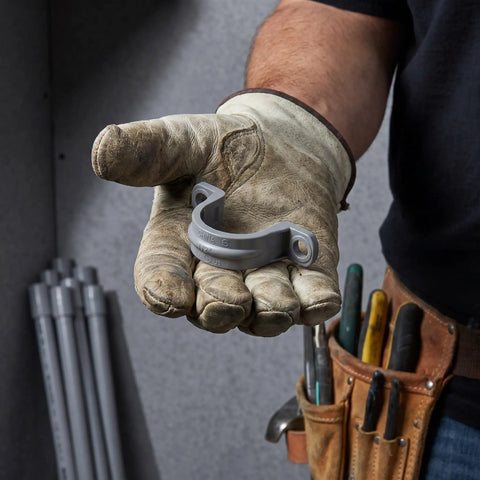 Killer Grip 20 Pack PVC Pipe Clamps Half Inch Conduit Straps held in gloved hand for secure wiring and cable routing installation.