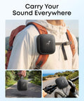 Boom Go 3i Palm Sized Portable Bluetooth Speaker attached to a backpack, ideal for hiking and camping, black.