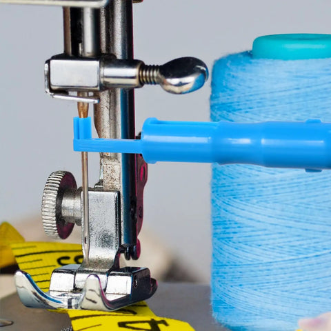Blue Automatic Needle Threader for Sewing Machines with spool of thread and tape measure near machine needle, close-up view