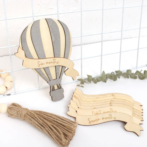 Wooden Hot Air Balloon Monthly Milestone Cards For Babies, My First Year Sign set on white background with greenery