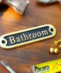 "No Soliciting Brass Door Sign For A Chill Home Traditional Style Wall Plaque Handcrafted Metal Decor Solid Brass Sign To Keep Unwanted Callers Out Classic Rustic Entryway Door Accent" displayed on a wooden surface with screws and tools.