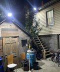 Backyard with Beefy 800W Solar Street Light With 80000 Lumens illuminating the area at night, mounted on a building wall.