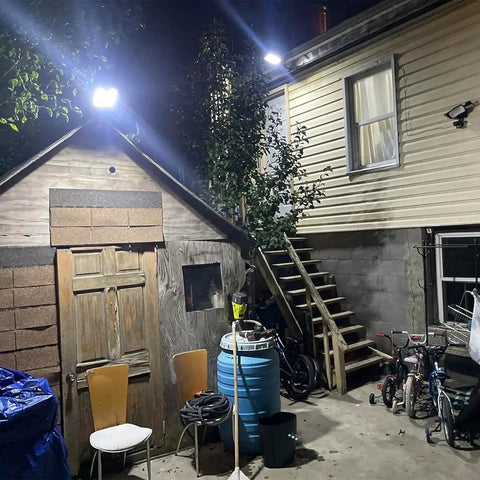 Backyard with Beefy 800W Solar Street Light With 80000 Lumens illuminating the area at night, mounted on a building wall.