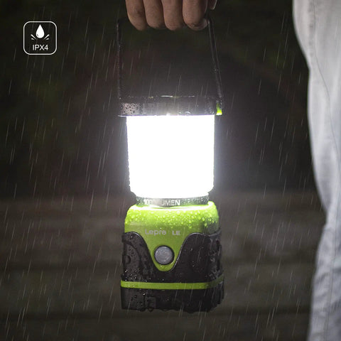 Person holding 1000 Lumen Battery Powered LED Camping Lantern With Four Light Modes in rain showing IPX4 waterproof feature.
