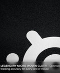 Close-up of the micro-woven cloth surface of the QcK Large Gaming Mousepad With Non Slip Silicone Rubber Base For Peak Tracking And Rock Solid Stability Pro Grade Surface Optimized For Gaming Sensors 490 mm By 420 mm Perfect For FPS MOBAs RTS MMO Play, showcasing its texture and logo.