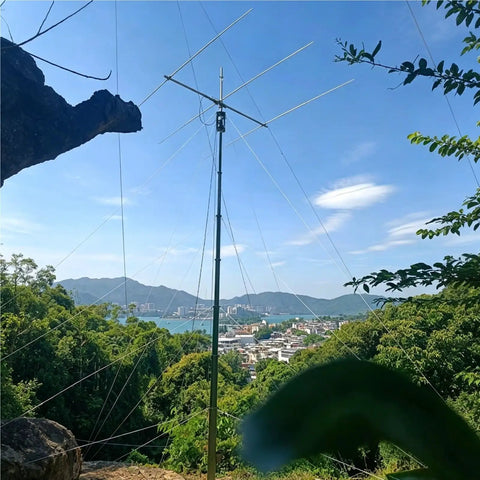Manual Winch Crank Telescopic Mast With Tripod Base supporting Ham Radio Antenna in a scenic mountain view, six meter height setup.