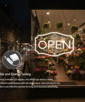 Lit Neon Open Sign For Business With Dimmable LED Warm White Glow, 16.5 By 10.5 Inch, Includes 12V 2A Adapter, Bright Visibility For Windows Walls Bars Cafes Salons Stores, Eye Catching Open Sign That Lights Up Front Window, displayed in a cozy flower shop window.