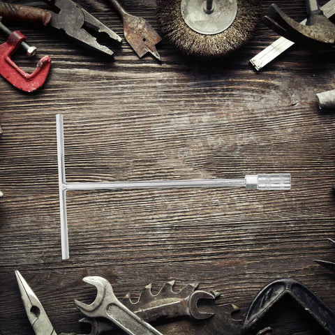 Ergonomic Steering Wheel T Handle Socket Wrench Made From Tough American Steel For Motorcycle Repair on a wooden table surrounded by tools.
