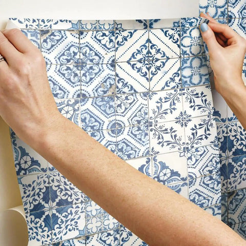 Hands applying blue Mediterranean tile peel and stick wallpaper no mess no water no fuss removable and repositionable.