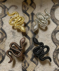 Snake Shaped Cabinet Knobs Set of 4 Dope Black Zinc Alloy Drawer Pulls and Door Handles on patterned fabric