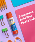 Glue stick with orange cap and All Purpose label next to pencils, paper clips, and paper, text: Permanent, Acid Free, Photo Safe.