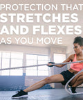Athletic woman in pink sports bra and black shorts pulling a rope in a gym.