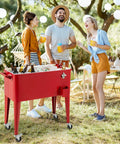 Three people enjoying drinks around a red 80 Quart Rolling Ice Chest Cooler On Wheels With Bottle Opener, Cap Catcher, And Bottom Storage Shelf.