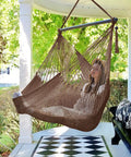 Woman relaxing on an Extra Large Hammock Swing Chair with Spreader Bar for indoor or outdoor kick back relaxing, dark brown.