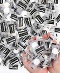Hands holding individually wrapped compressed towels, part of the 200 Count Cotton Compressed Towels Pack Disposable Face Towels.
