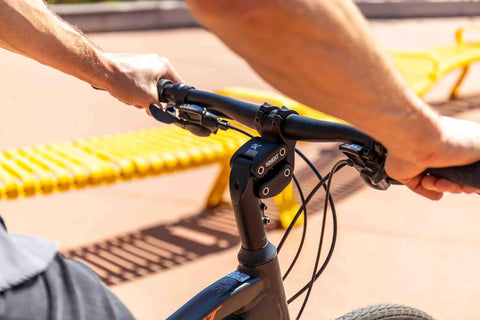 Cyclist using Suspension Stem For Bicycle Handlebar With Adjustable Shock Absorption to reduce fatigue on a sunny day.