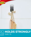 Small Satin Nickel Bath Hook With Water Resistant Strips Holds Up To 1 Lb No Tools Needed Super Easy Install For Damage Free Bathroom Organization in use, holding brush on tiled wall.