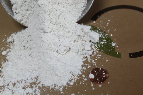 Close-up of Gypsum Powder For Clay Soil Solution Grade Calcium Sulfate Soil Amendment For Lawn And Garden Improving Drainage And Aeration, 97 Percent Purity, pH Neutral, Made In USA, Two Pounds, with a penny for scale.