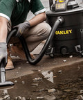 Man using Powerful Five Point Five Peak HP Wet Dry Vacuum With Twelve Gallon Tank Three In One Shop Vacuum on wet floor.