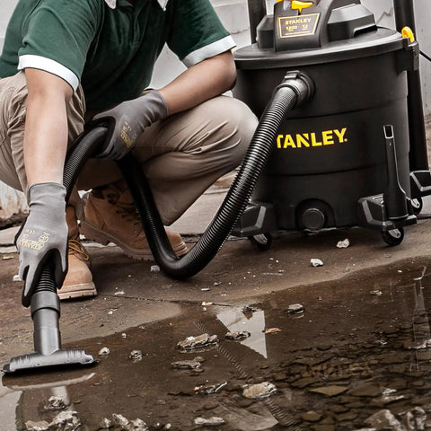 Man using Powerful Five Point Five Peak HP Wet Dry Vacuum With Twelve Gallon Tank Three In One Shop Vacuum on wet floor.