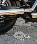 Beefed Up Alloy Steel Motorcycle Sprocket Chain Gear With Screw And Retainer Plate beside a bike tire on gravel