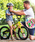 Father helping son with helmet, Glow In The Dark Bike Spoke Beads Set For Kids, 144 colorful plastic round beads on bicycle spokes.