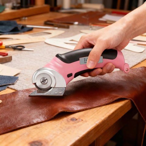 Heavy Duty Cordless Electric Scissors With Fast Usb Rechargeable Power And Self Sharpening Steel Blades For Slick Cuts Through Denim Fabric Leather Carpet And Stubborn Cardboard In Nifty Pink cutting brown leather on worktable.
