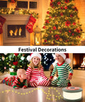 Children in striped pajamas sitting near a decorated Christmas tree by a fireplace with stockings, a string light in front.