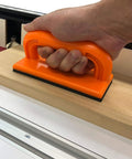 Heavy Duty Five Piece Woodworking Safety Kit With Beefy Push Blocks And Grippy Push Sticks To Keep Your Digits Well Clear From Nasty Kickback On Table Saws And Routers, showing orange push block in use on wood.