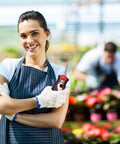 Woman gardener holding Ultra Light Long Reach Pruning Shears for garden and florist use in greenhouse, smiling in apron.